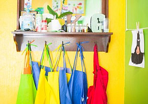 Children's painting aprons hung up in a row